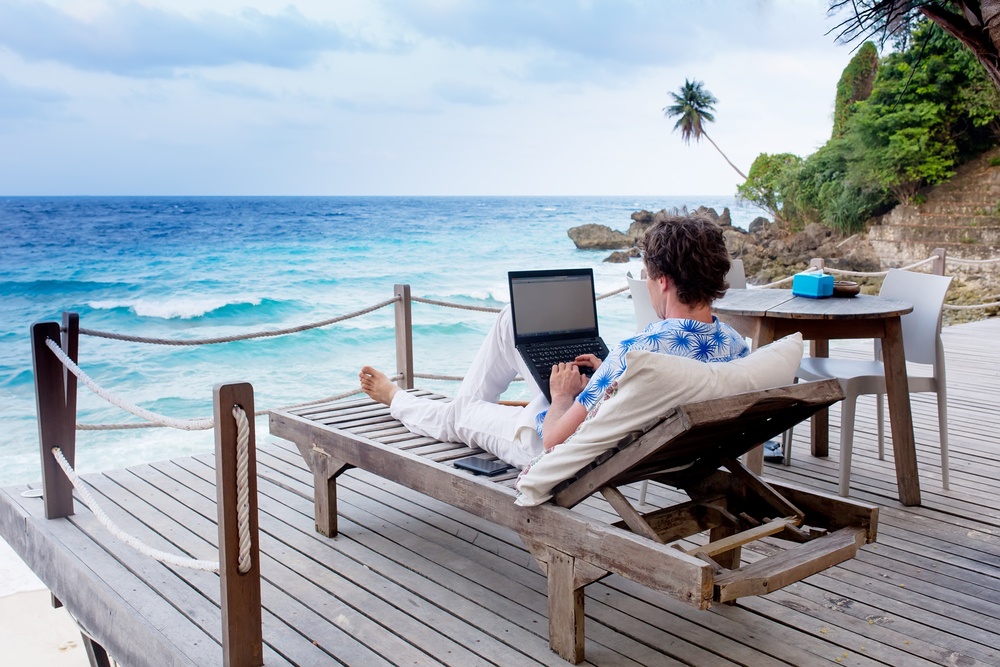 a person sitting on a chair with a laptop on the beach
