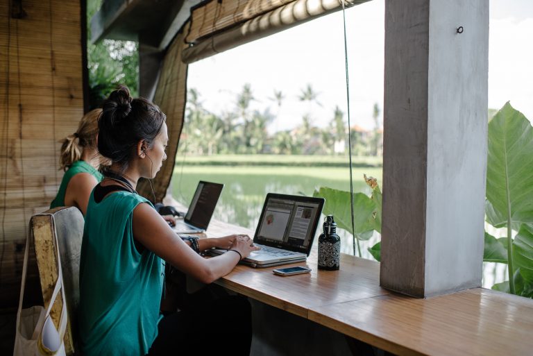 a woman sitting at a desk with laptops