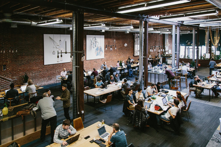 a group of people sitting at tables in a room with a brick wall