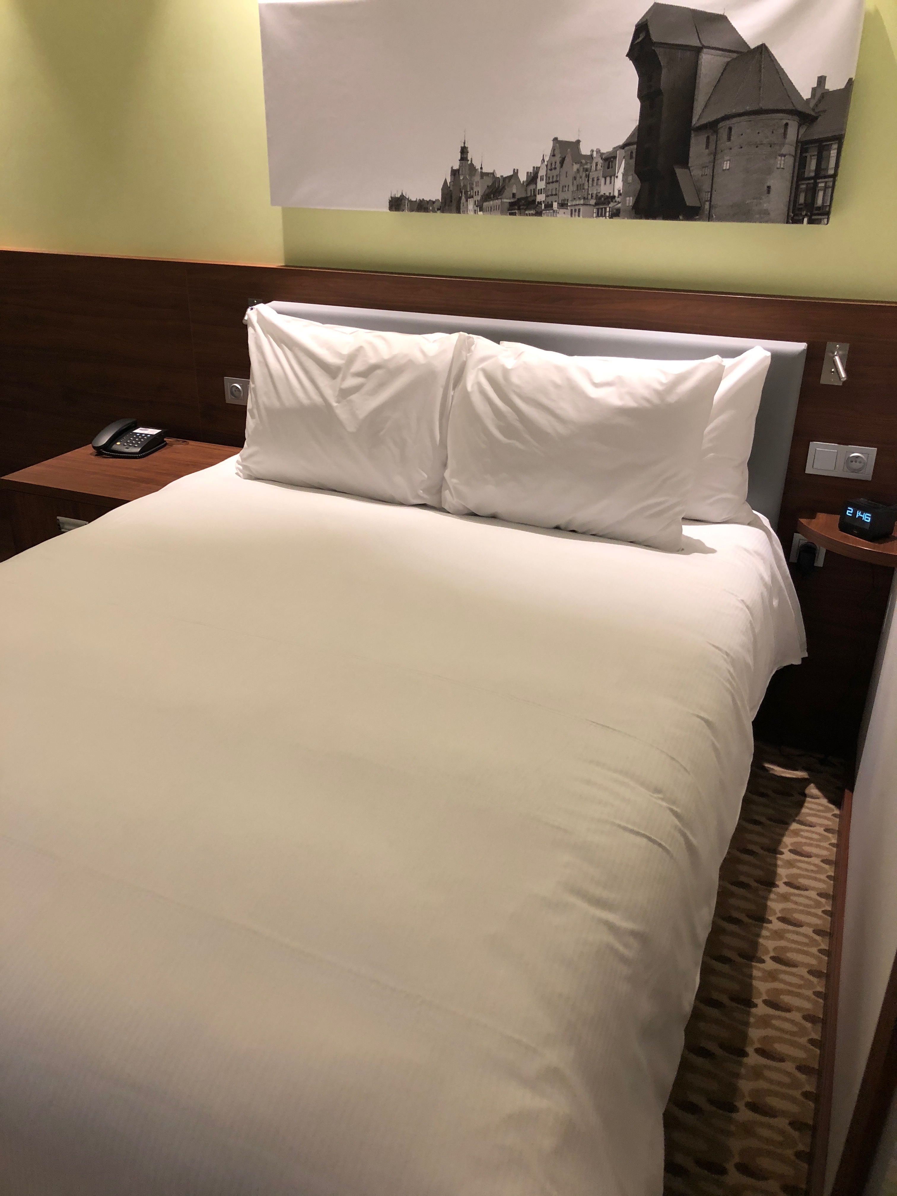 a bed with white sheets and a wood headboard