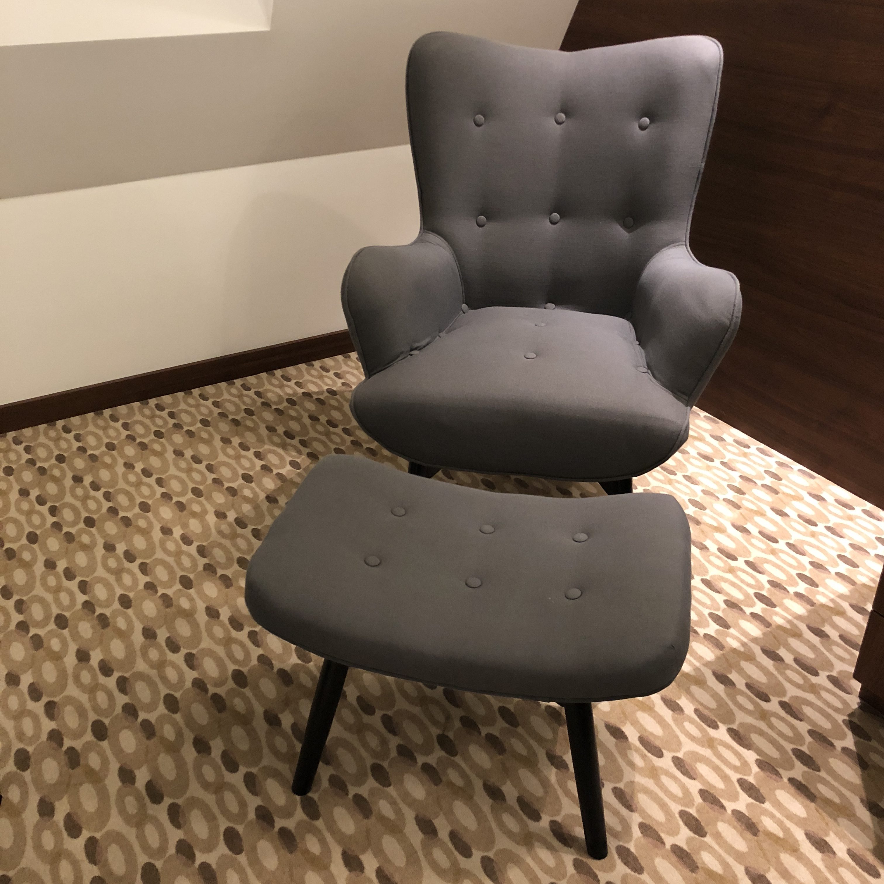 a grey chair and ottoman on a carpeted floor