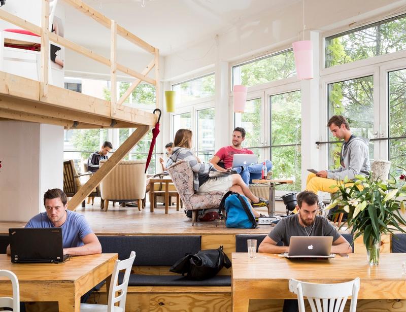 a group of people sitting at tables with laptops