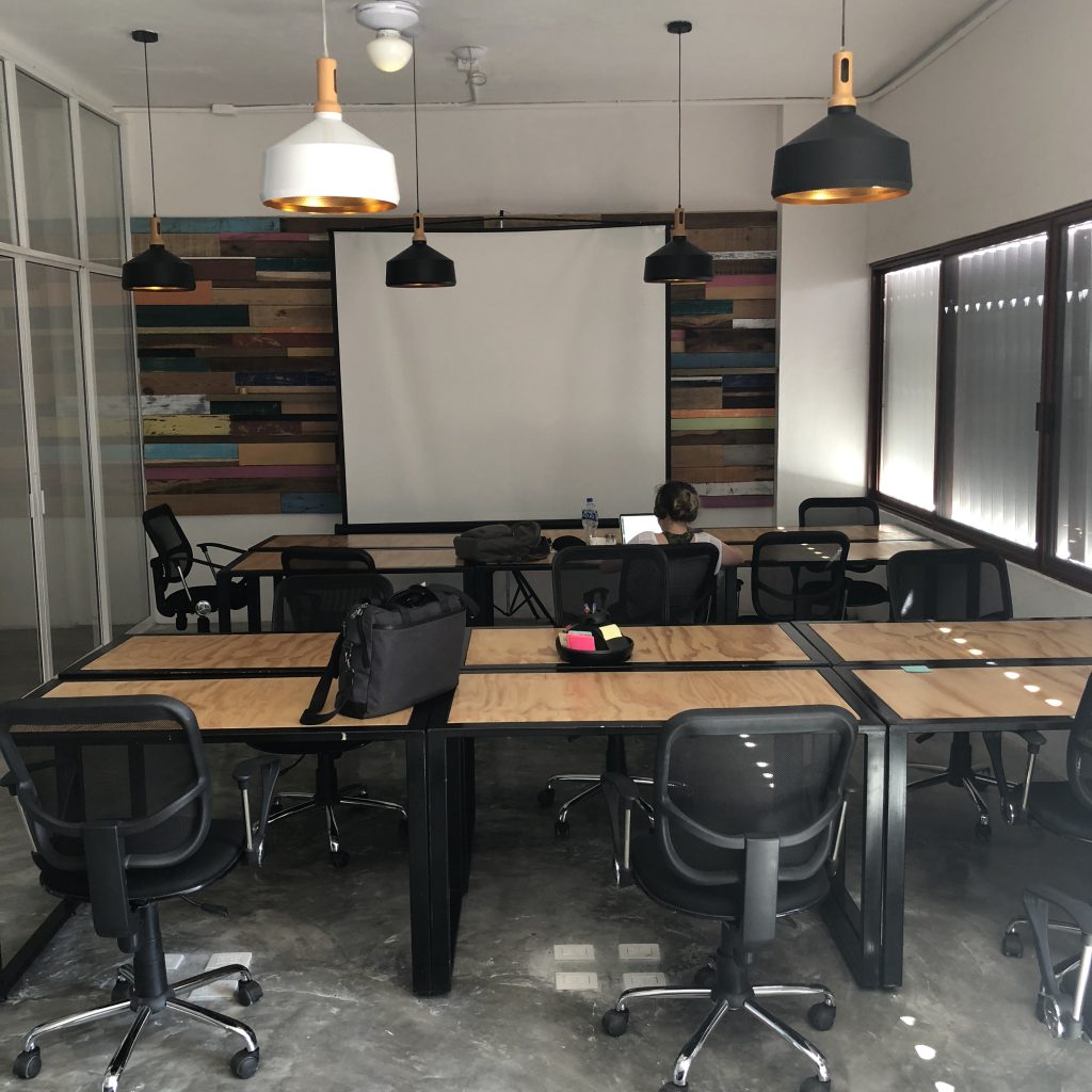 a room with a white screen and tables and chairs