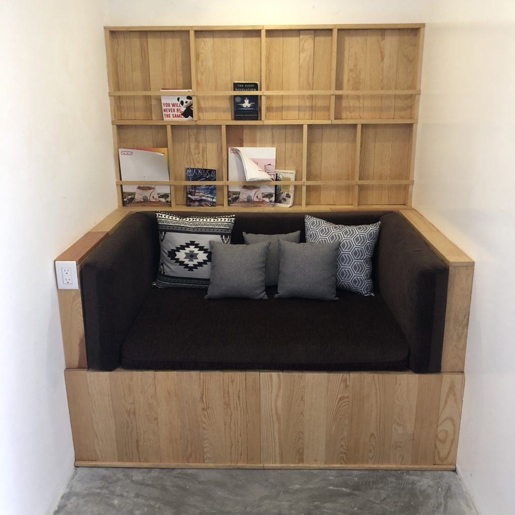 a couch with pillows and a shelf in the corner
