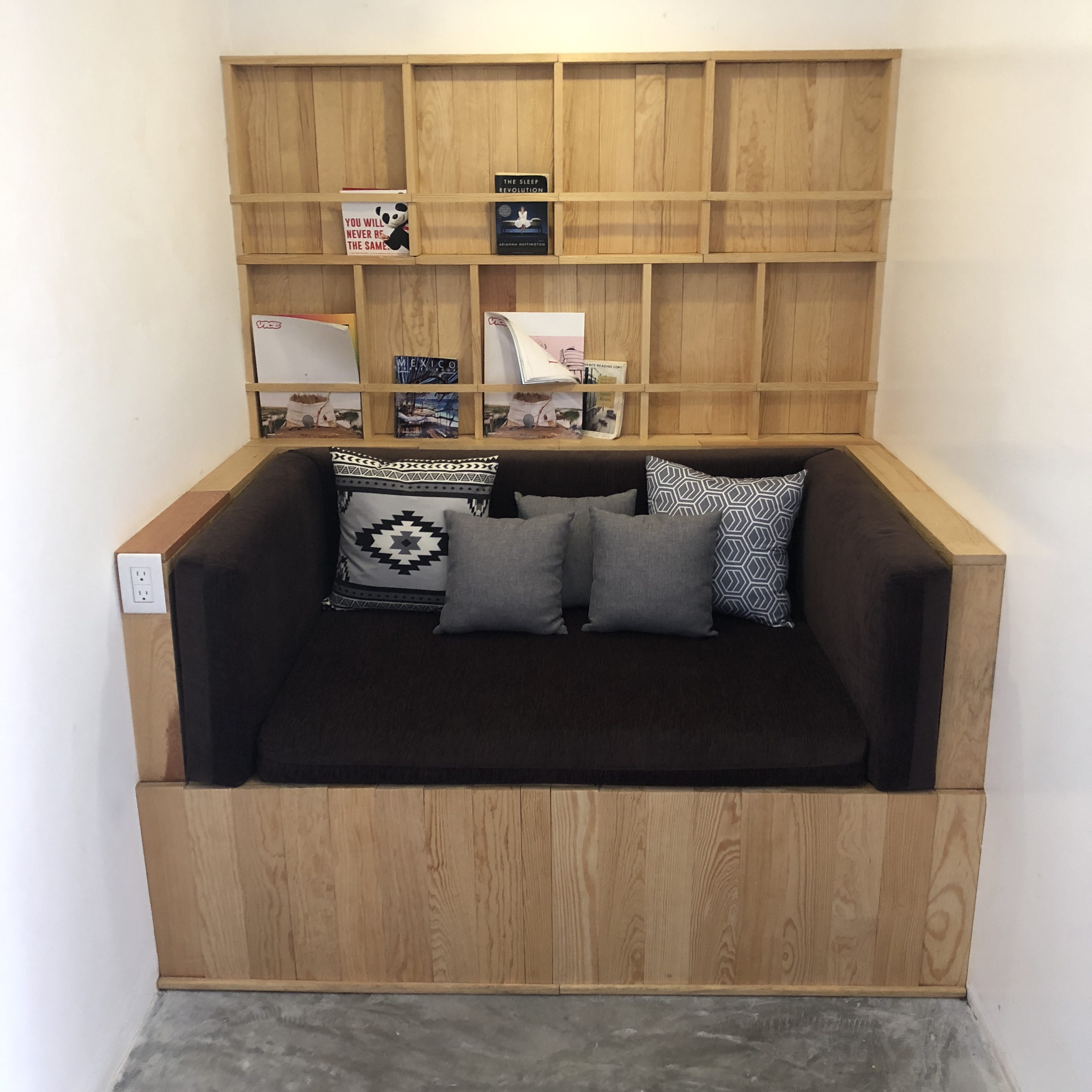 a couch with pillows and a shelf in the corner