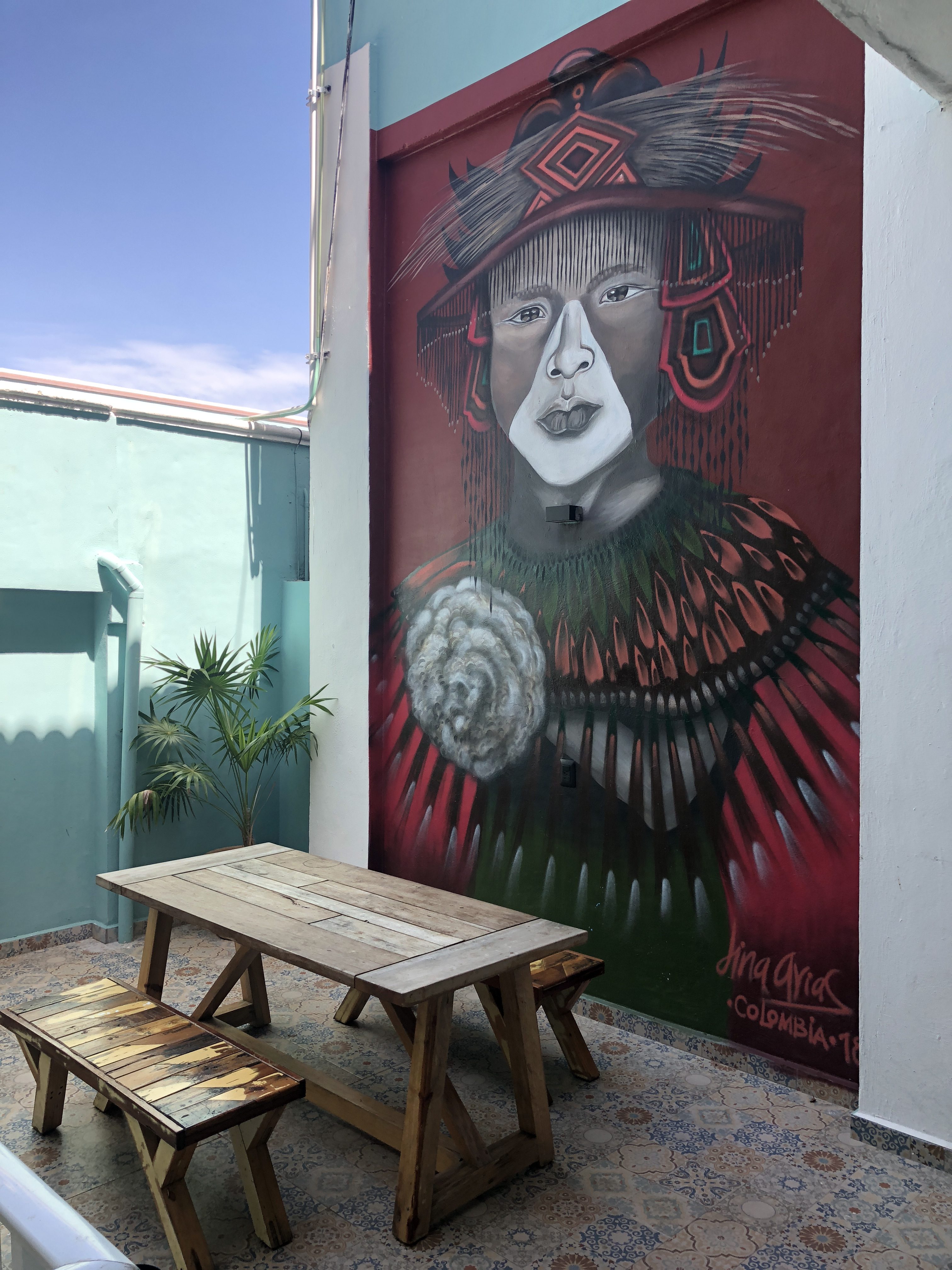 a painting of a woman on a wall next to a bench