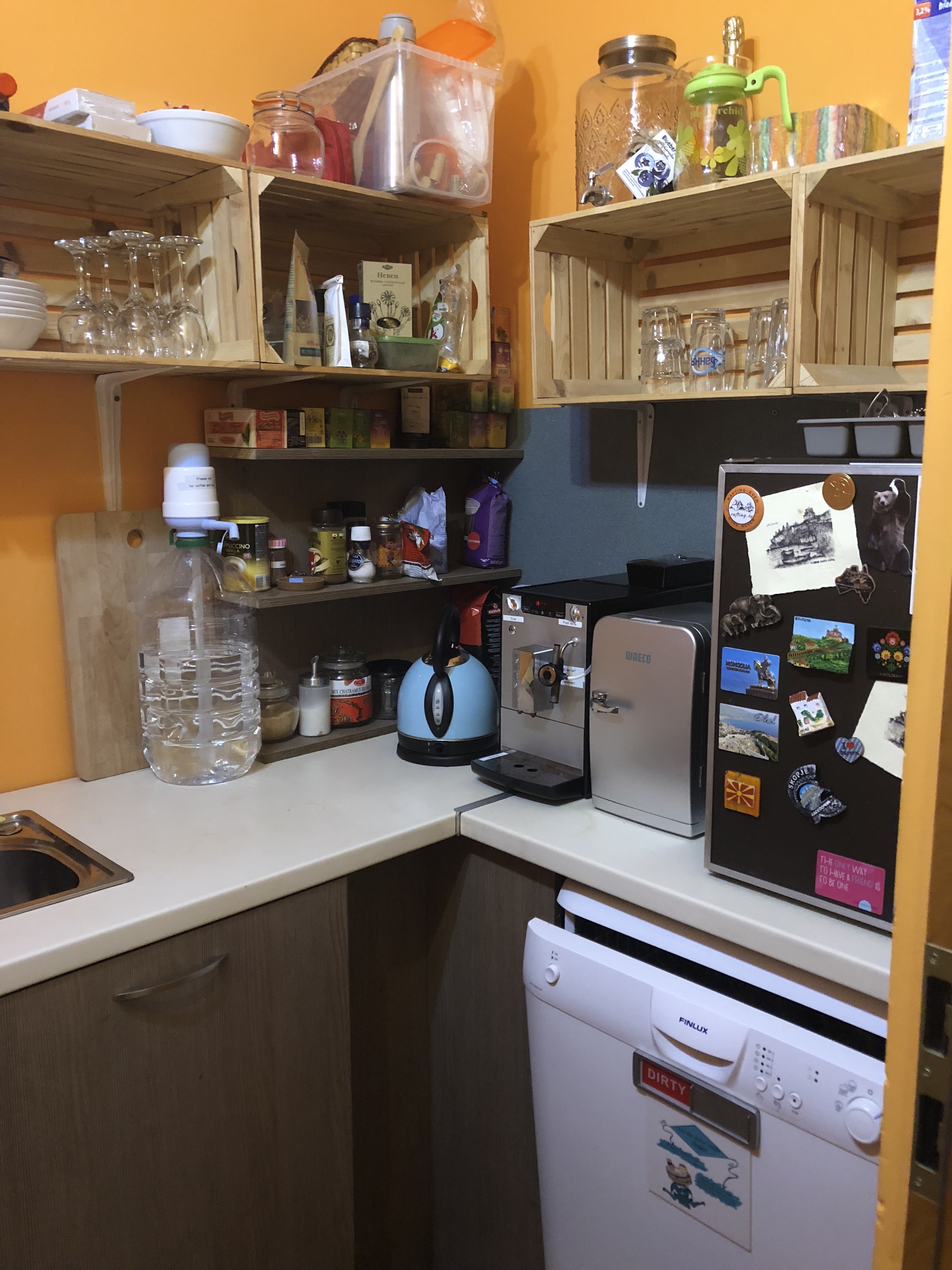 a kitchen with a white dishwasher and shelves