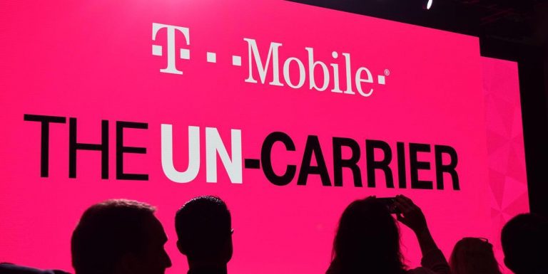 a group of people standing in front of a large pink sign