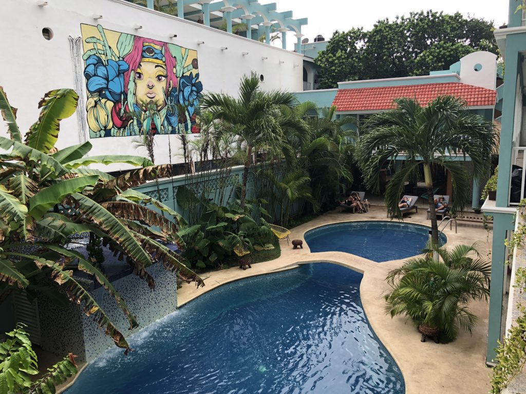 a swimming pool with palm trees and a mural on the wall