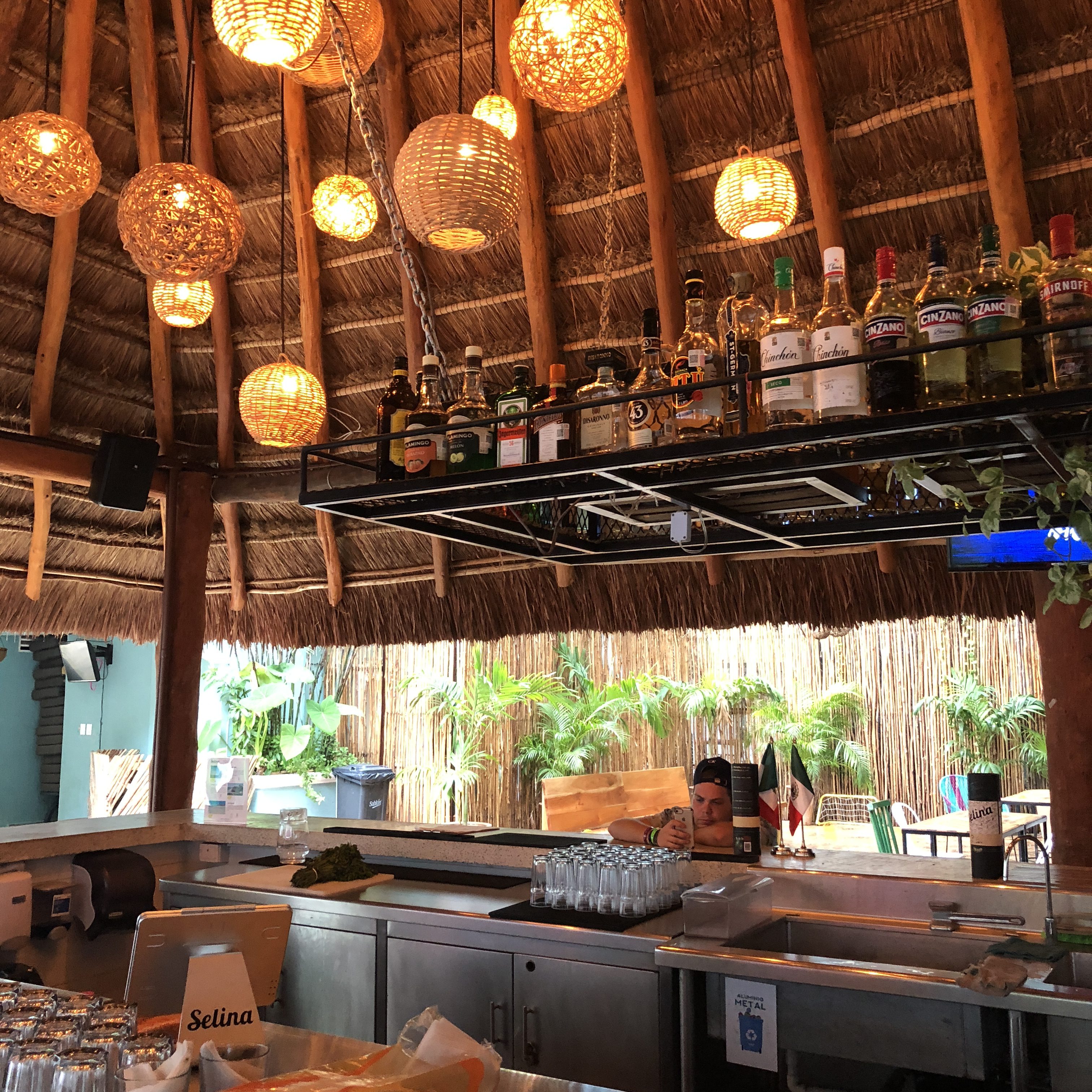 a bar with a thatched roof and bottles of alcohol