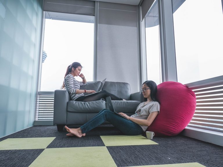 two women sitting on a couch with a laptop