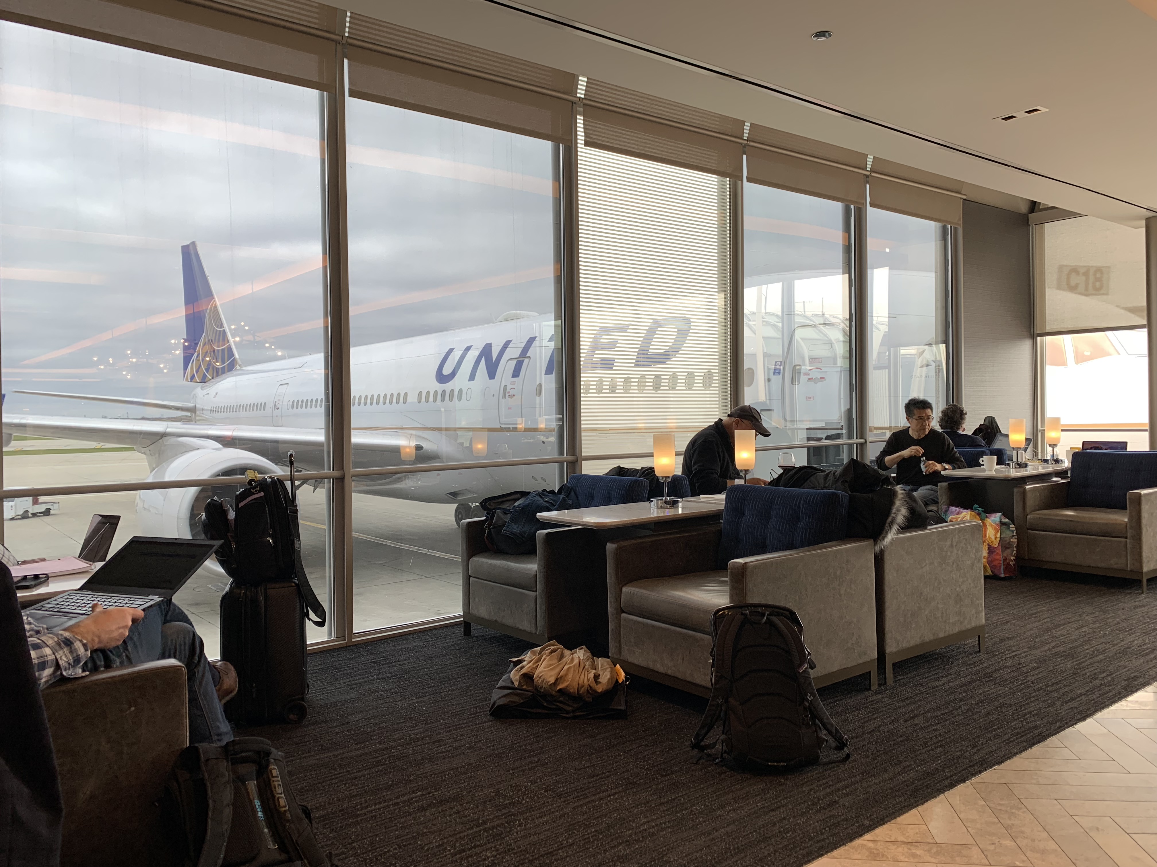 people sitting in a lounge area with a plane in the background