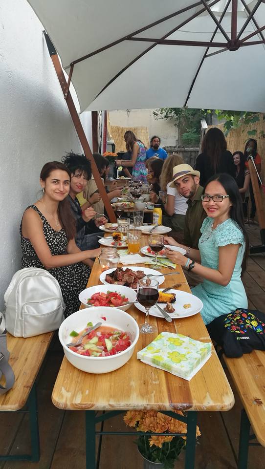 a group of people sitting at a table with food and drinks