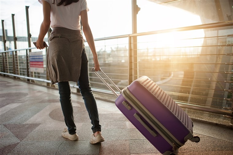 a woman pulling a purple suitcase