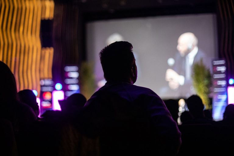 a man sitting in front of a large screen