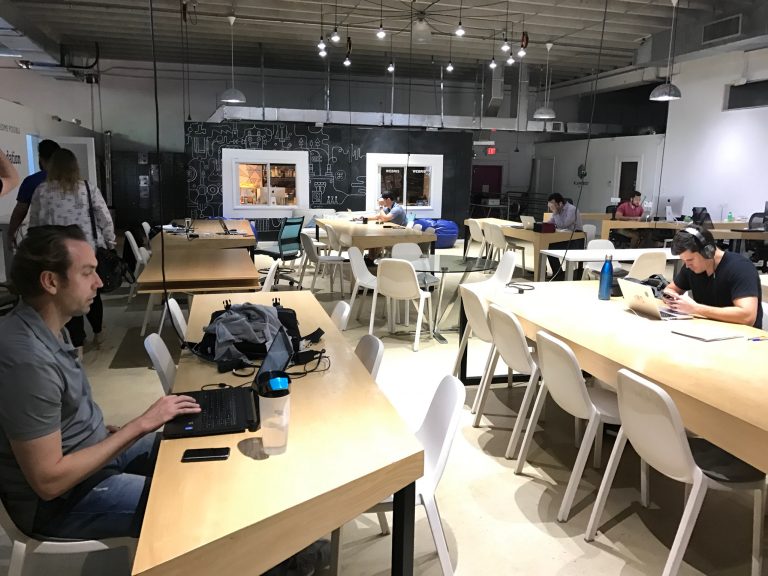 a group of people sitting at tables with laptops