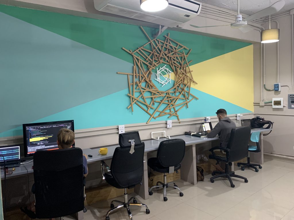 people sitting at a desk in front of a wall with a large artwork