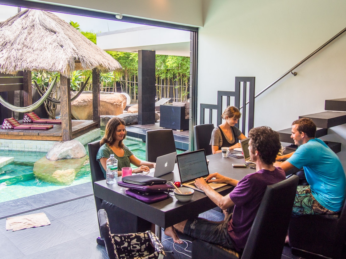 a group of people sitting around a table with laptops