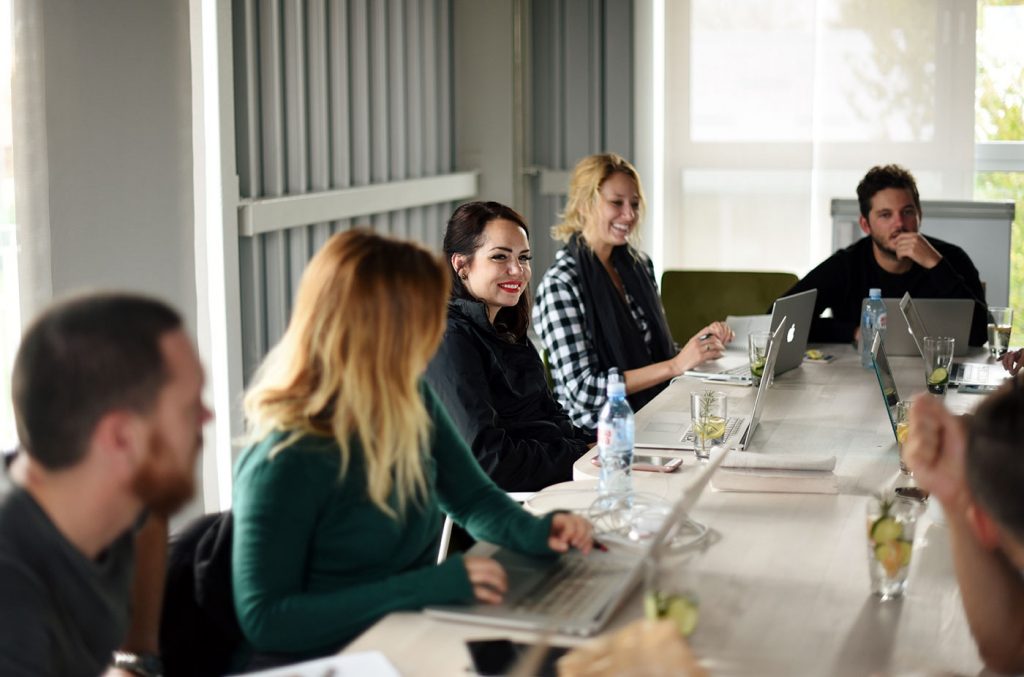 a group of people sitting at long tables with laptops