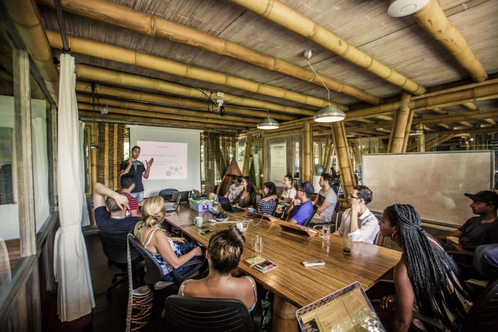 a man standing in front of a group of people sitting around a table