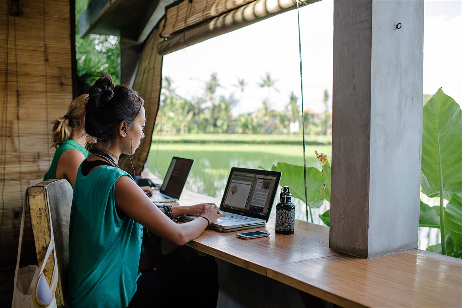 a woman sitting at a table with laptops