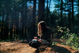 a woman sitting on a rock in the woods