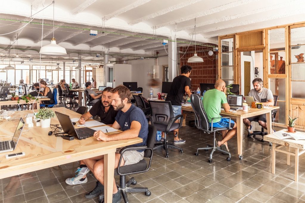 a group of people sitting at tables with laptops