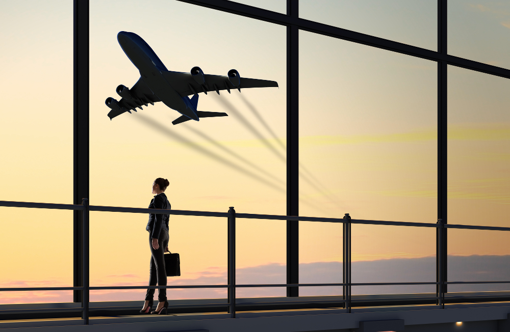 a woman standing on a bridge looking at an airplane