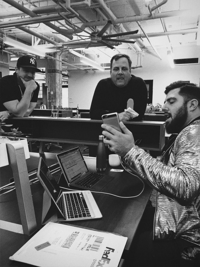 a group of men sitting at a table with laptops and a microphone