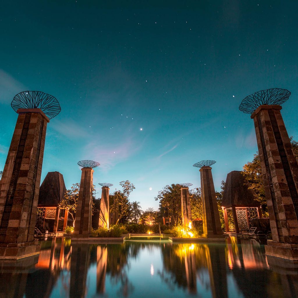 a pool with pillars and a lit up fountain