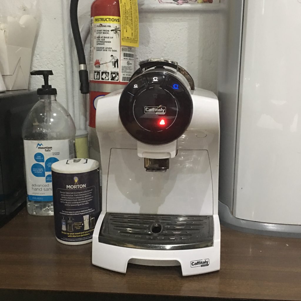 a white coffee machine with a red light on it