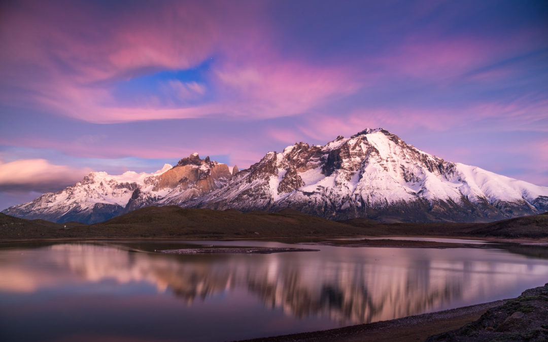 a lake with snow covered mountains in the background