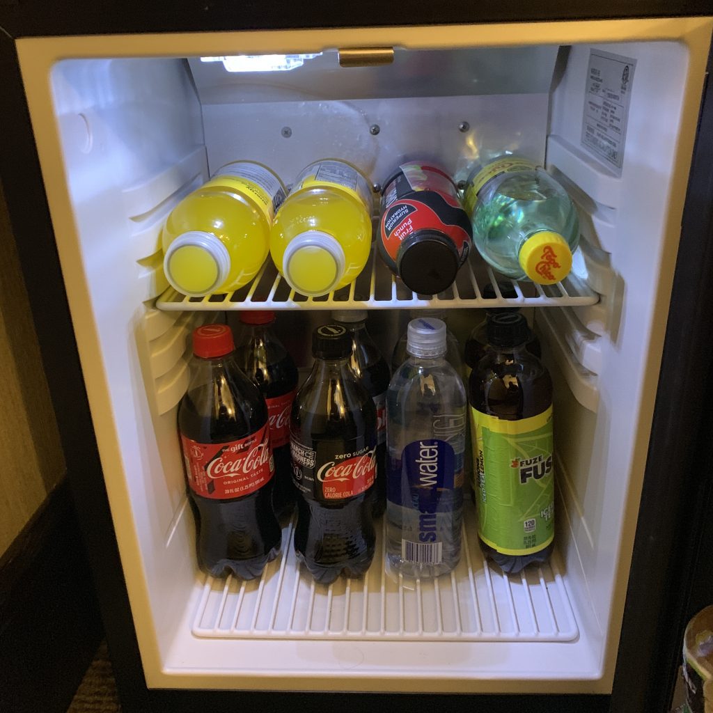 a small refrigerator with bottles of soda and other beverages