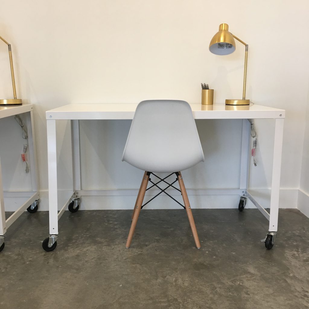 a white chair and desk with gold lamps on it