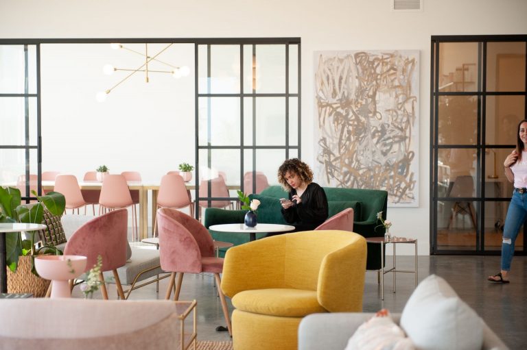 a woman sitting on a couch in a room with chairs and a table