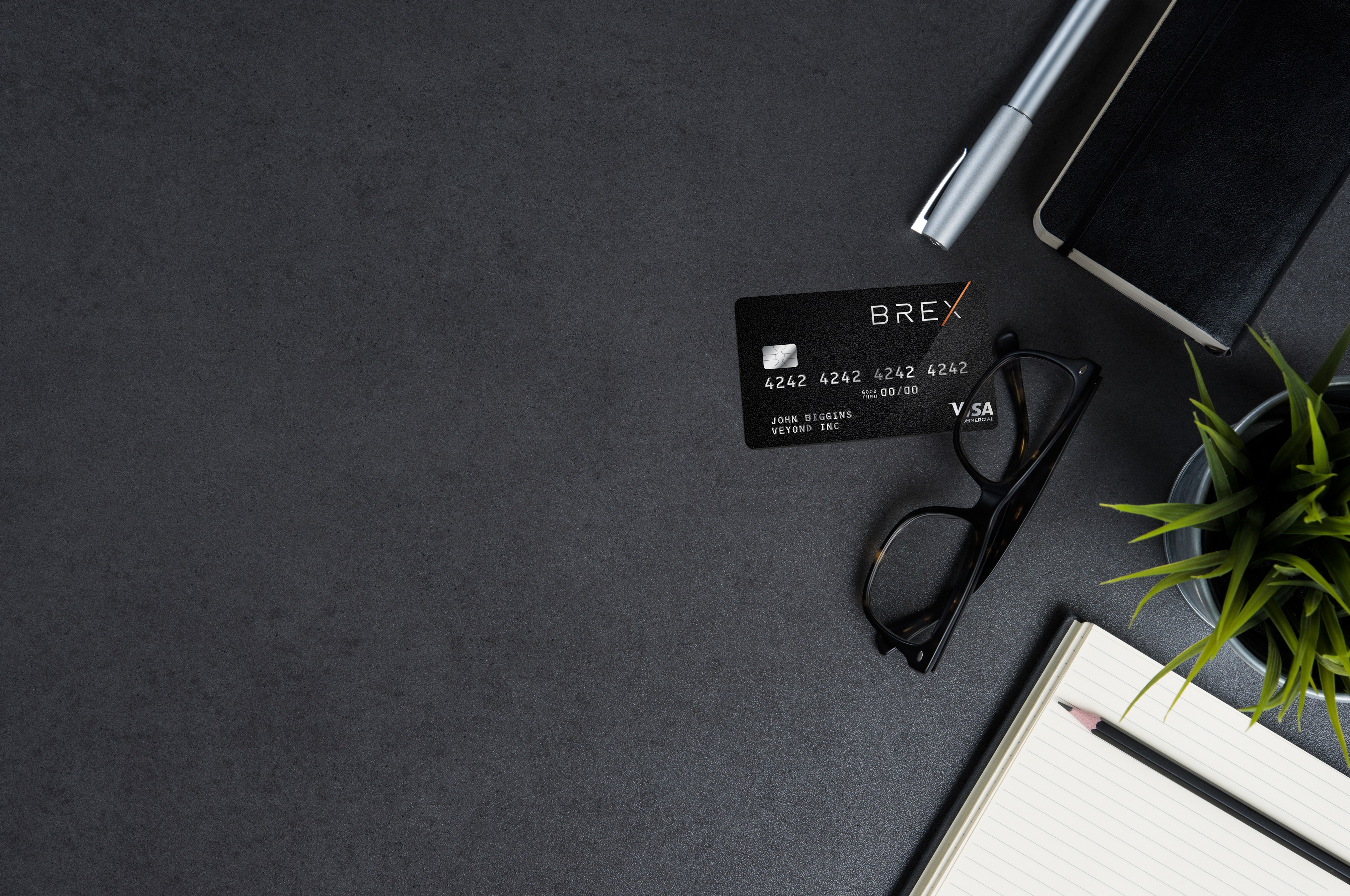 a desk with a credit card and glasses and a pen