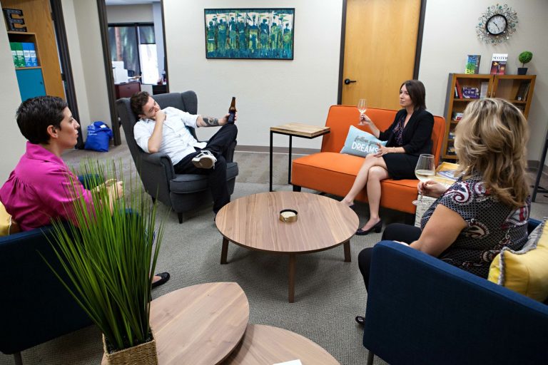 a group of people sitting in chairs and drinking wine