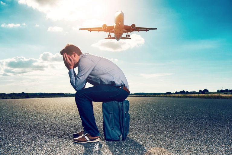 a man sitting on a suitcase with his head in his hands