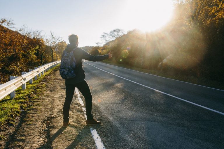 a man standing on a road with his thumb up