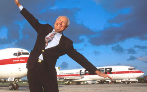 a man in a suit standing in front of an airplane