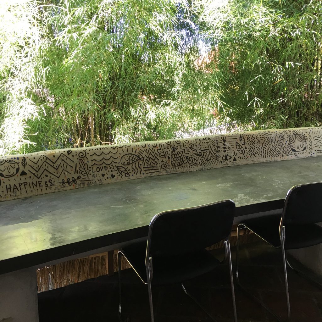 a table with chairs and a wall with trees in the background