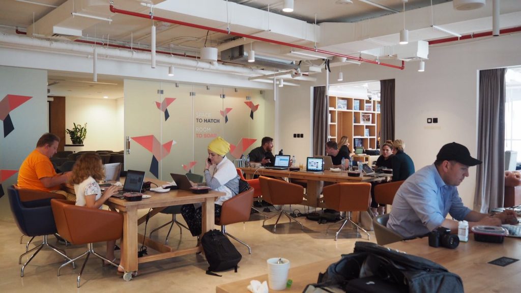 a group of people sitting at tables with laptops