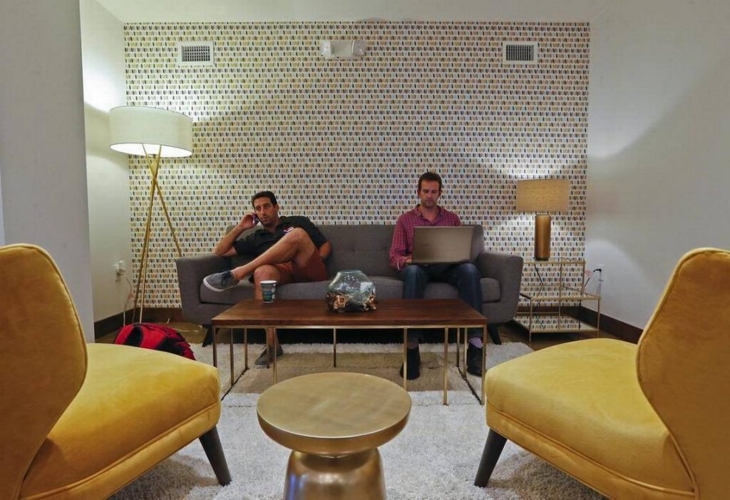 two men sitting on a couch with a laptop