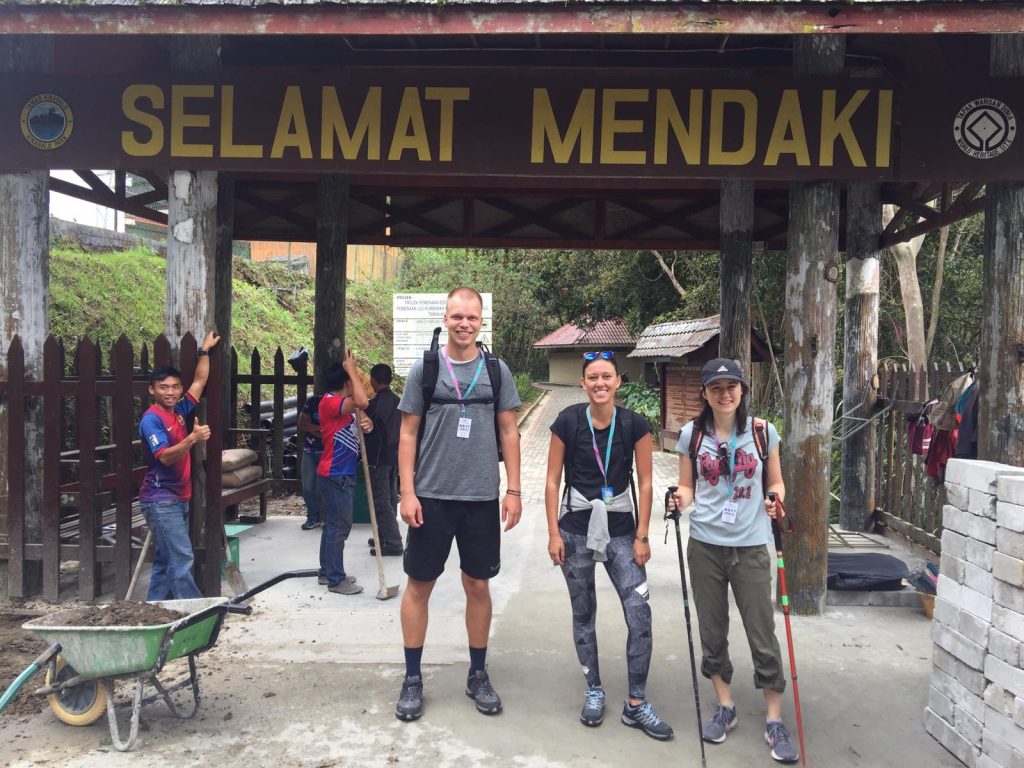 a group of people standing under a wooden structure