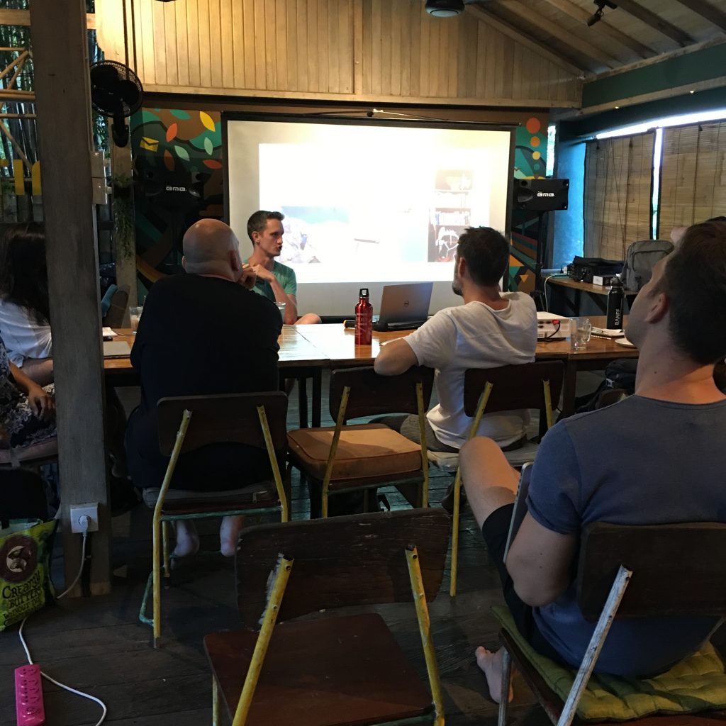 a group of people sitting at a table looking at a screen