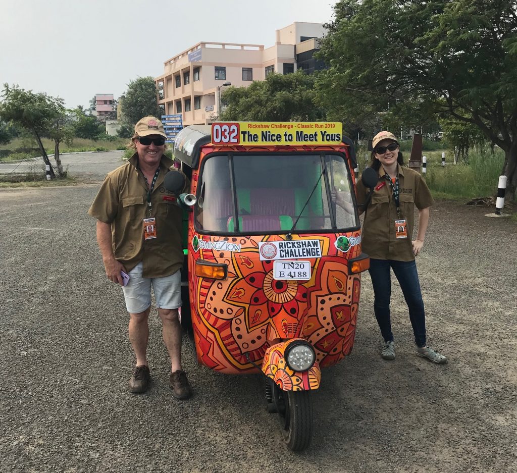 a man and woman standing next to a colorful vehicle