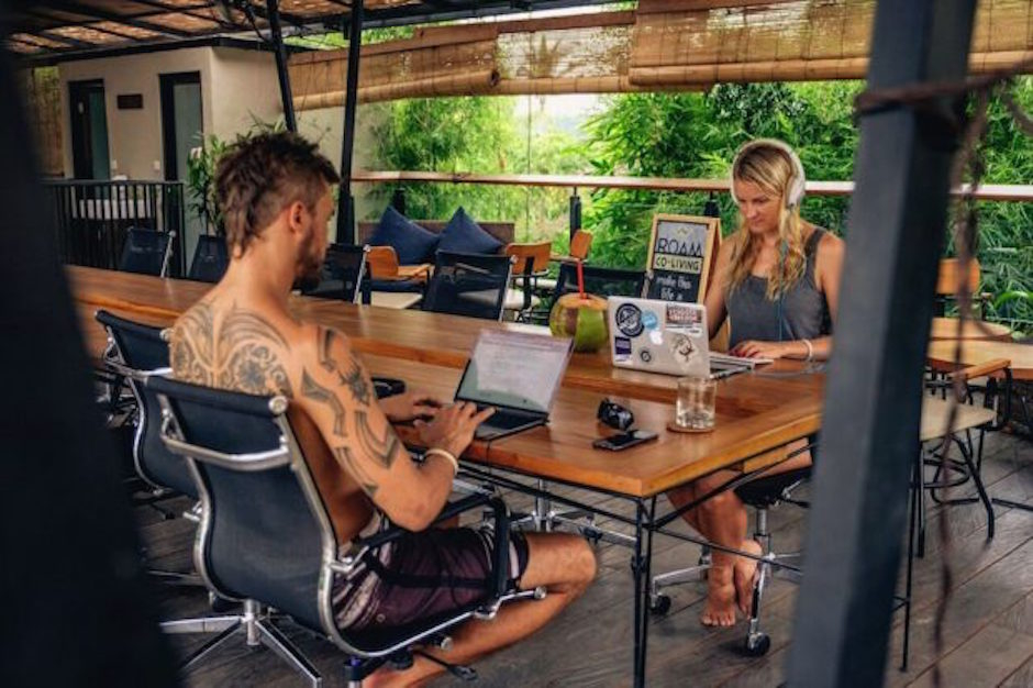 a man and woman sitting at a table with laptops