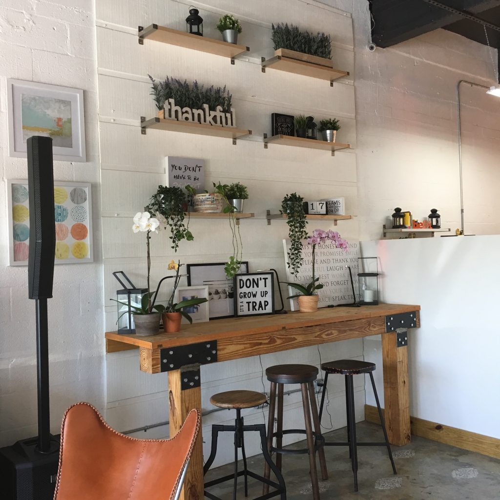 a room with a table and stools and plants on the wall