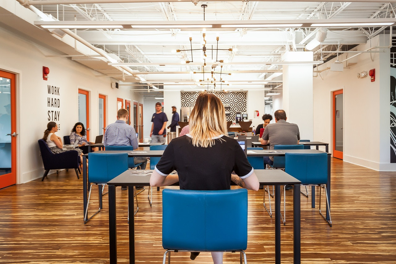 a woman sitting at a desk in a room with people