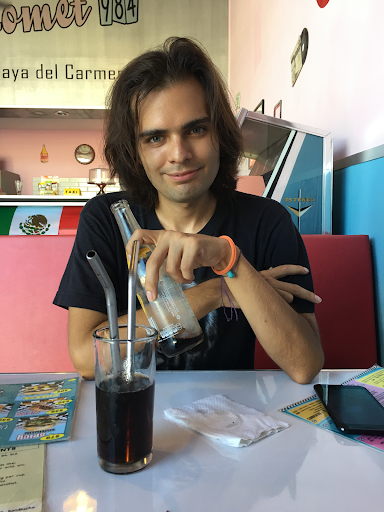 a man sitting at a table with a drink and straws